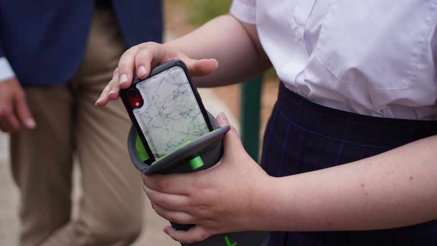 A pair of hands hold a phone being placed into a grey pouch