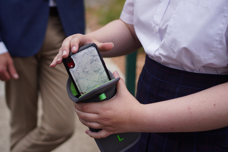 A pair of hands hold a phone being placed into a gray pouch