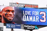 A big screen reads "Love for Damar" with a photo of Buffalo Bills player Damar Hamlin displayed at an NFL game.