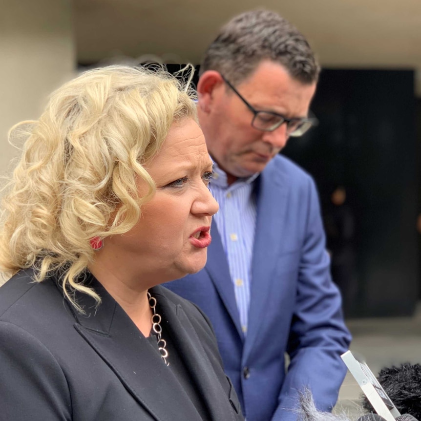 Jill Hennessy speaking at a press conference with Daniel Andrews in the background.