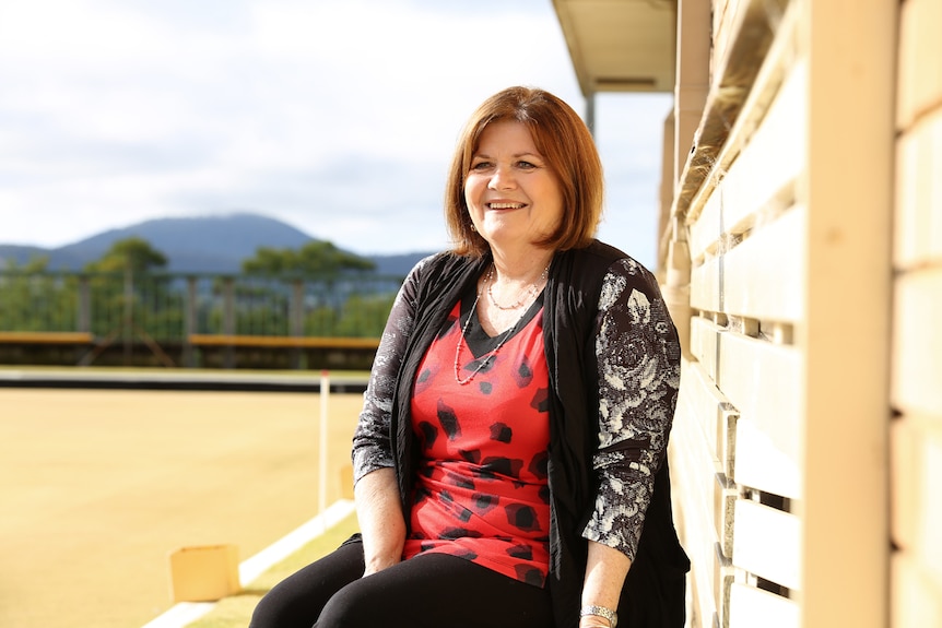 A woman sits next to a building