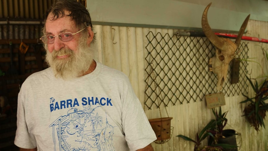 Man with grey bushy beared smiling at camera with bull skull in background.