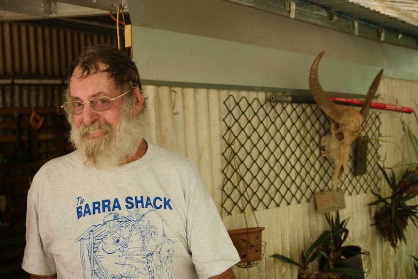 Man with grey bushy beared smiling at camera with bull skull in background.