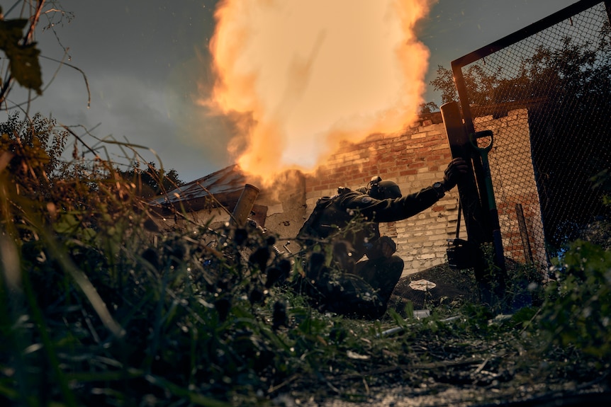 Soldiers take cover as a mortar fires