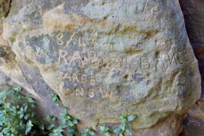 An engraved rock featuring the words R A Bryan, Taree, NSW.
