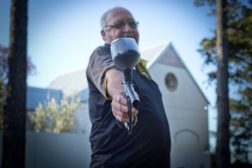 A private security guards aims a paintball gun used to shoot at raiding baboons.