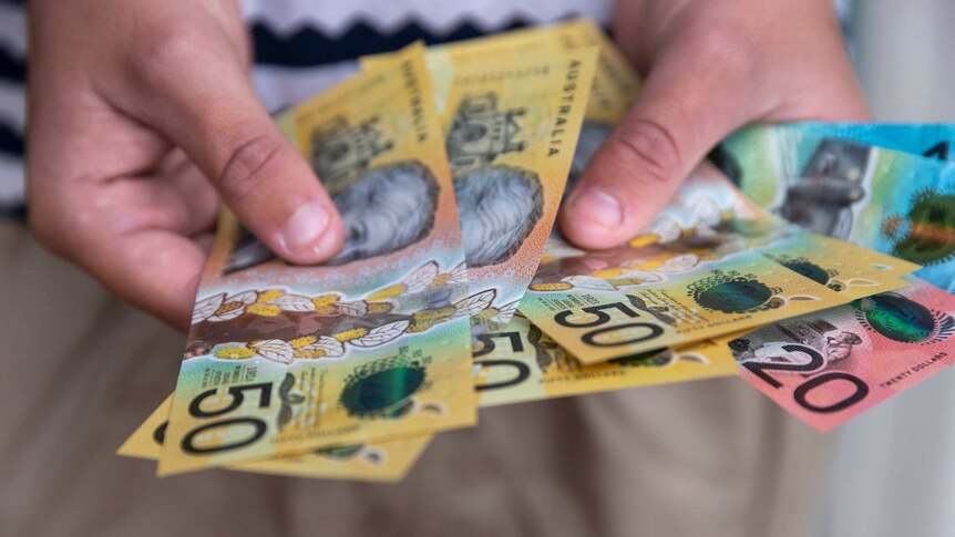 hands holding Australian cash notes