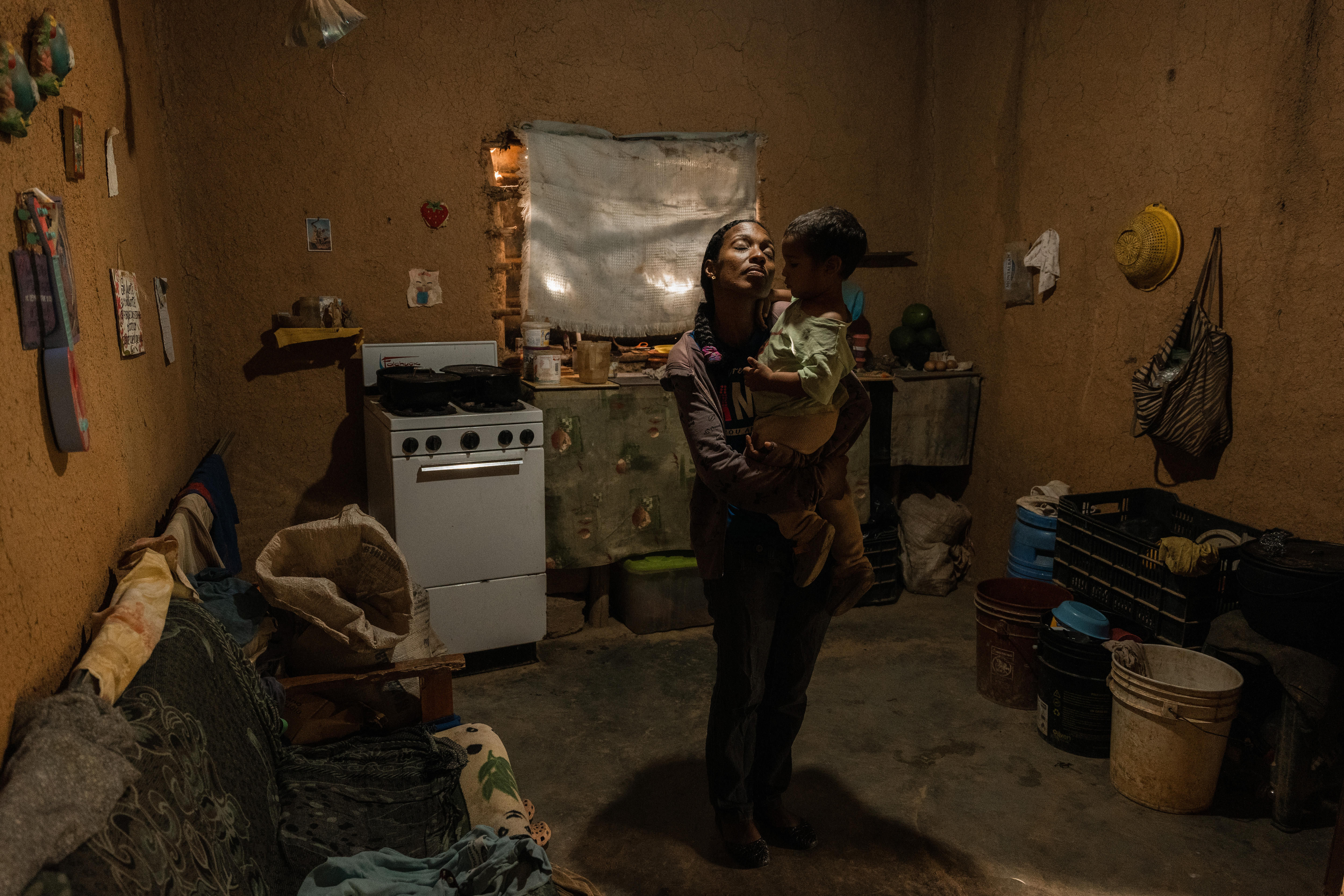 Yrelys Jimenez holds her son, Yonder Lopez-Jimenez, under a hole carved in the roof of the family home by heavy rain