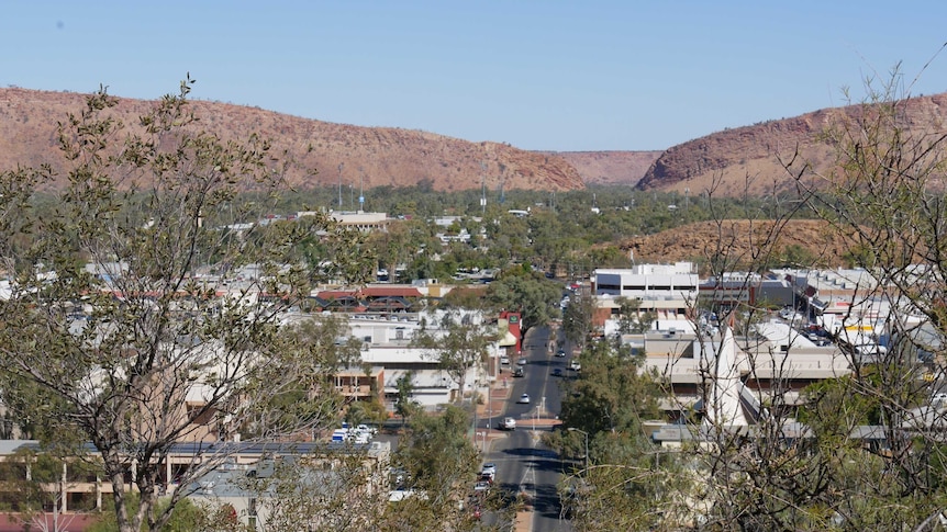 Aerial shot down the main street of a desert town dotted with trees.