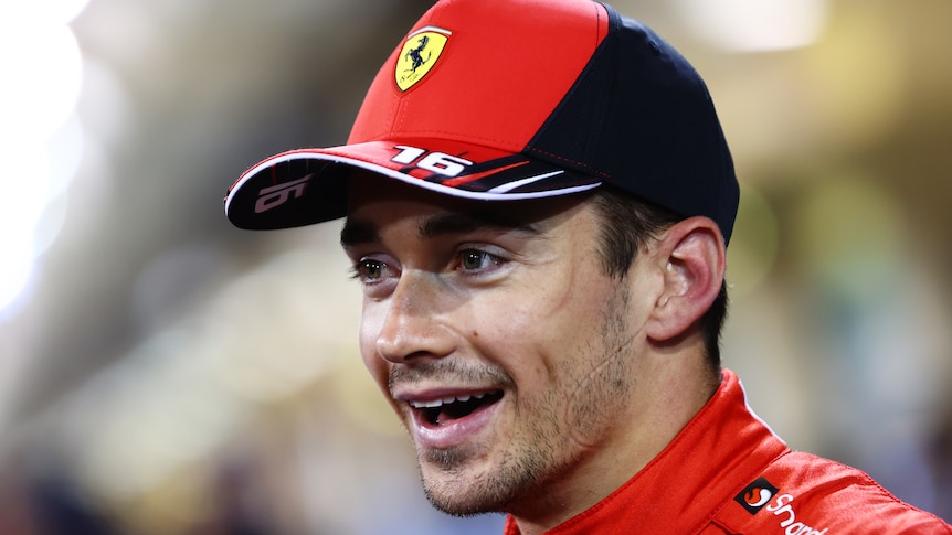 A man wearing a Ferrari hat smiles.