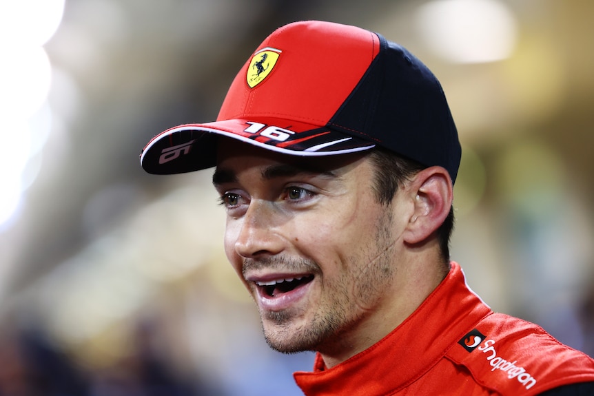A man wearing a Ferrari hat smiles.