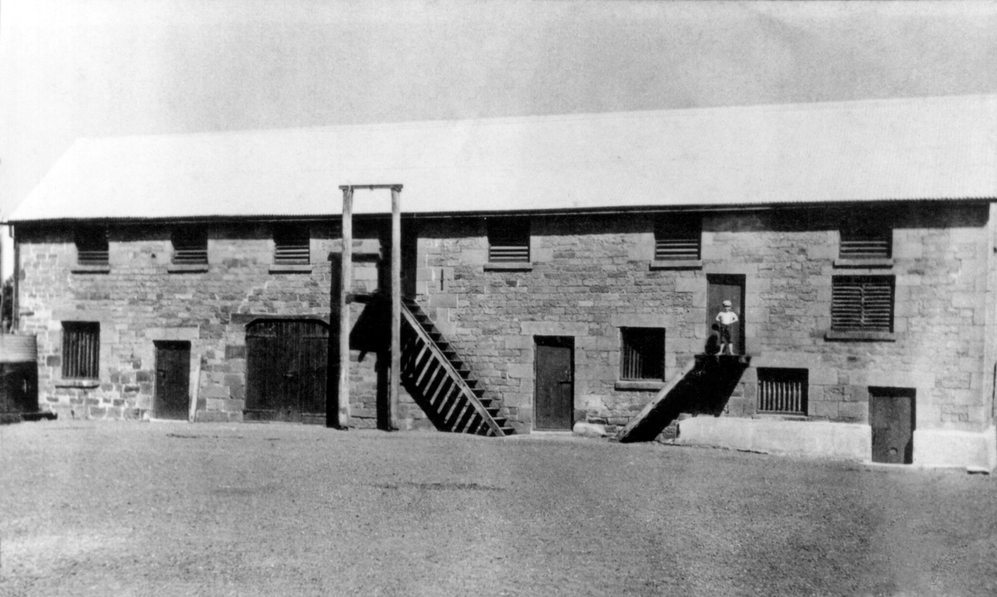 Black and white photo of little boy in front of Tocal building in 1890.