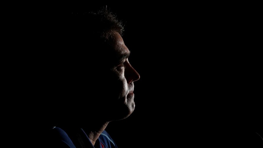 Brad Scott appears in profile on a black background with his face in faint light