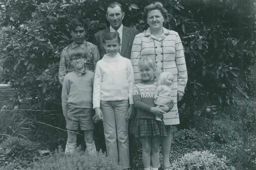 Indigenous poet Ali Cobby Eckermann and her adopted family pose for a group photo in front of a tree.