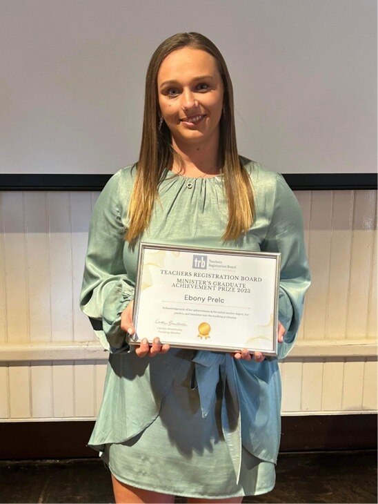 a young woman with brown hair holds a framed award