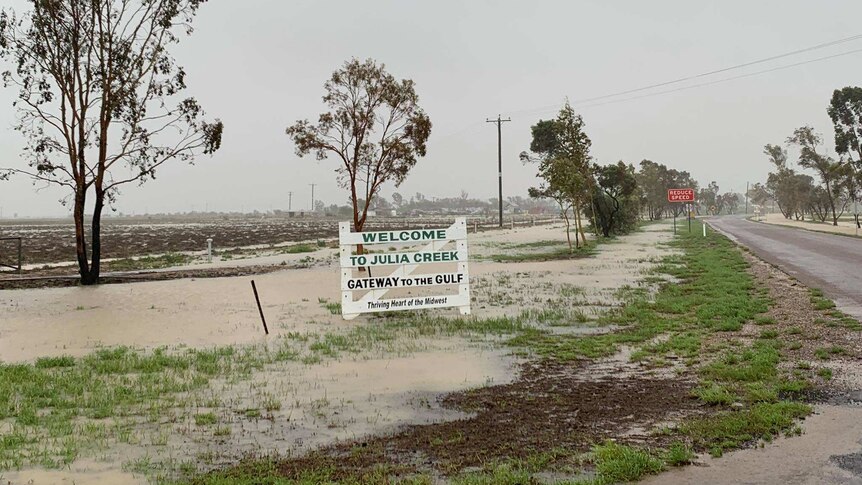 A welcome sign at Julia Creek in flood water after 230 millimetres of rain was recorded during the weather event.