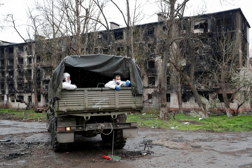 Two emergency management specialists sit in the back of a truck looking out.