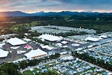 An aerial shot of a music festival with the sun low behind it.