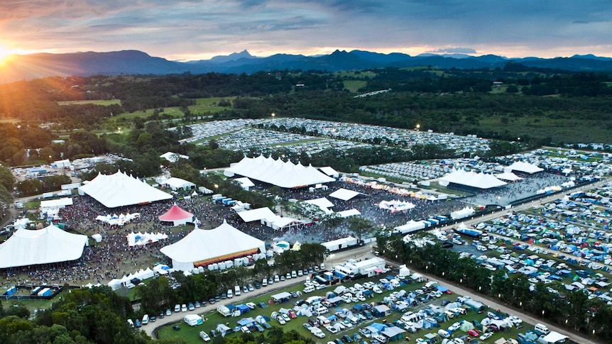 An aerial shot of a music festival with the sun low behind it.