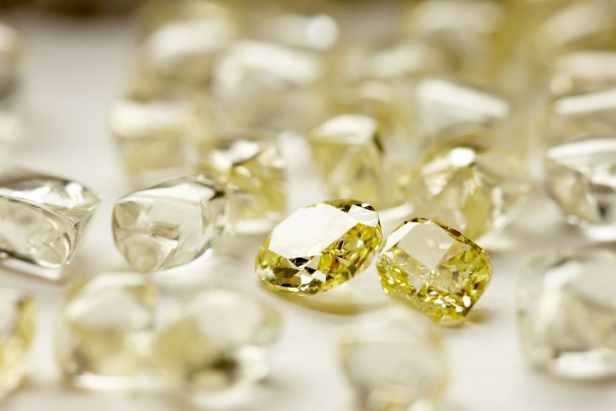 A large number of yellow diamonds lie on a flat surface.