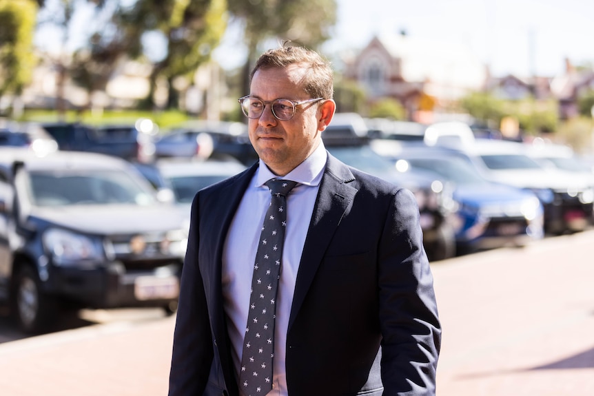 A man in a suit walking into court.  