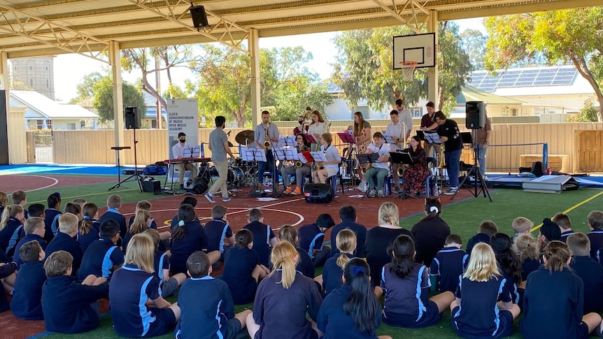 School students in blue uniform watch a band perform.