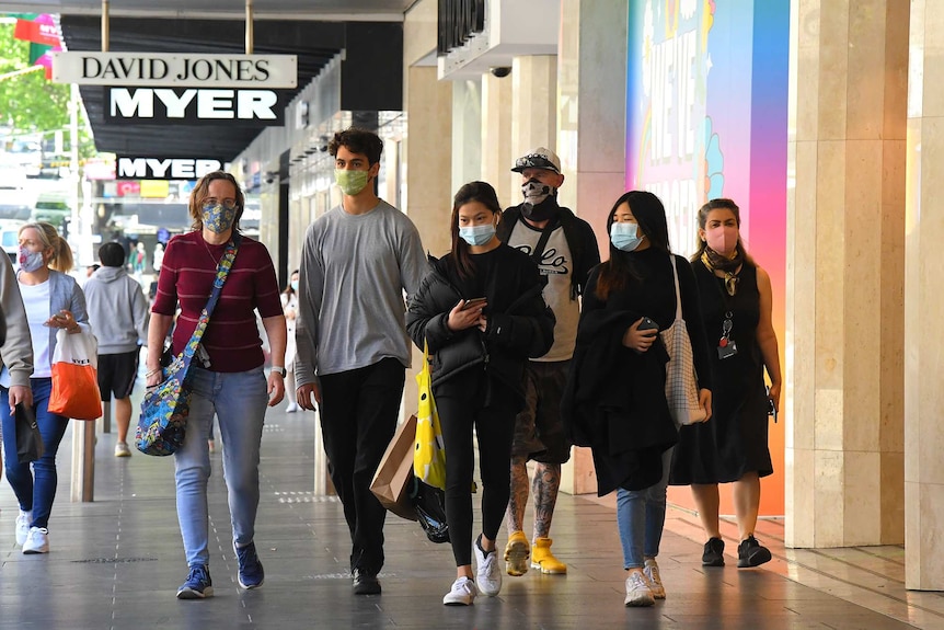 A crowd of people walk through a shopping mall