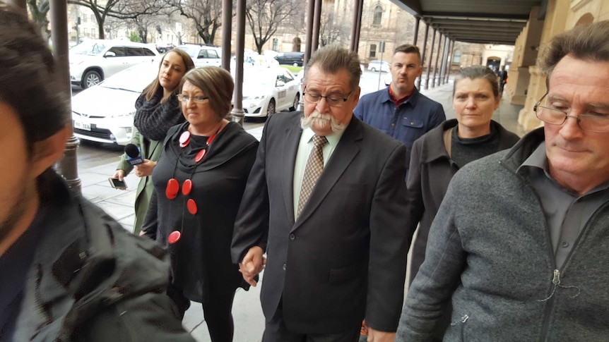 A man walks from the court house surrounded by people