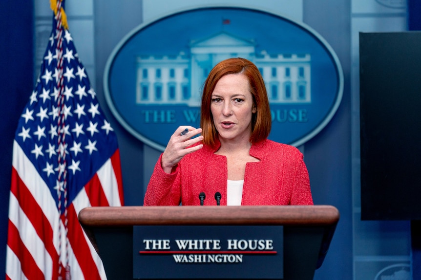 A woman makes an address from a podium labelled "The White House - Washington"