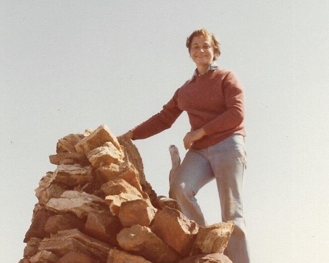 A woman stands on a rock