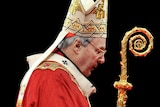 George Pell in full robes, holds a crook against a black background.