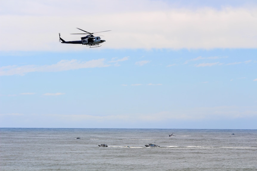 A helicopter hovers above the ocean