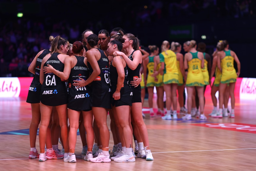 The Silver Ferns stand in a circle with their arms around each other as the Diamonds do the same in the background