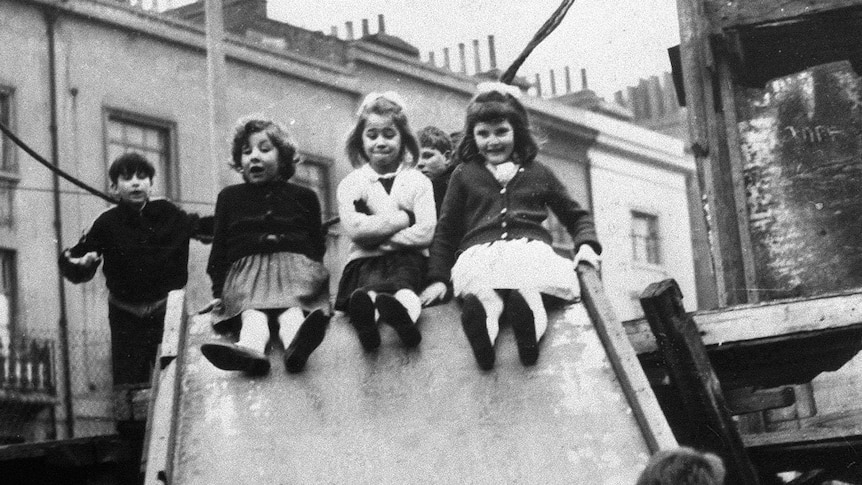 A black and white photo of children in the 60s playing on playground equipment, the image is dominated by three little girls.