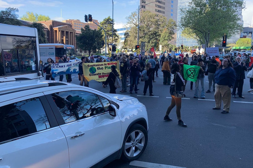 Protesters walking in Melbourne's CBD hold signs and banners and block traffic.