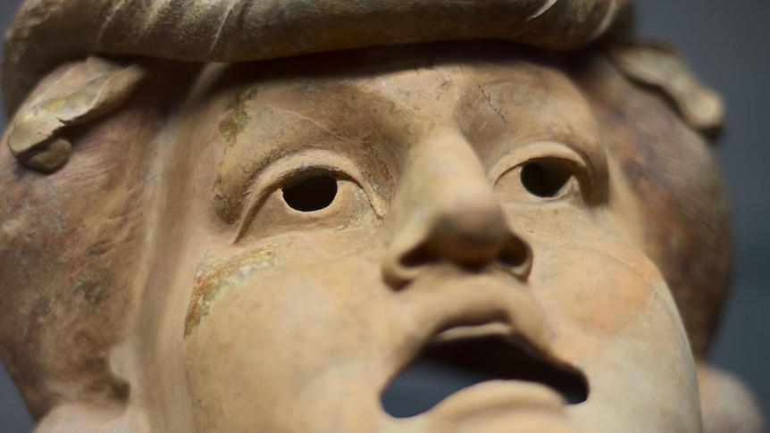 A theatre mask shows a tragic expression.