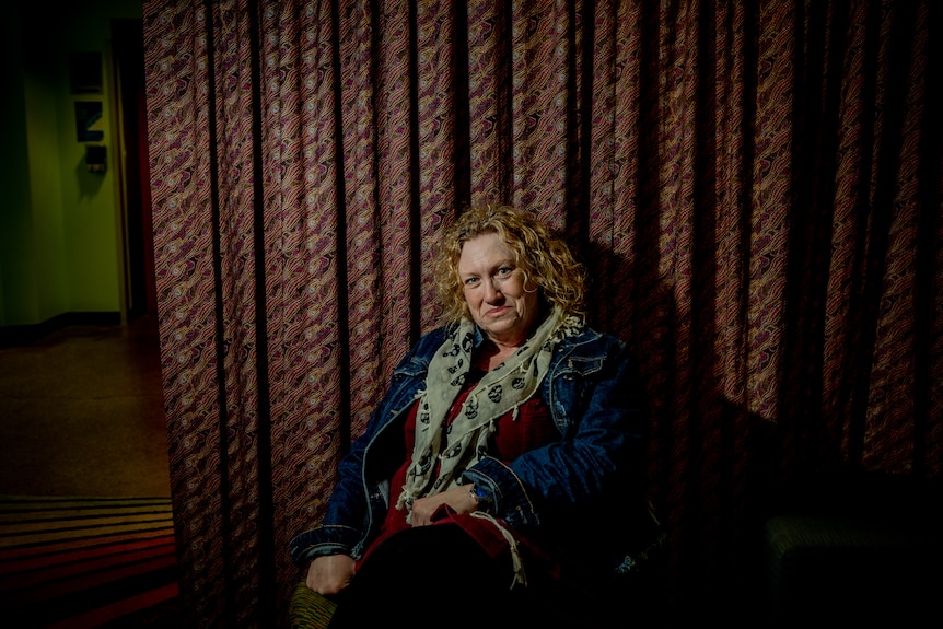 Leah McLeod sitting in front of a curtain with an intricate pattern, smiling at the camera.