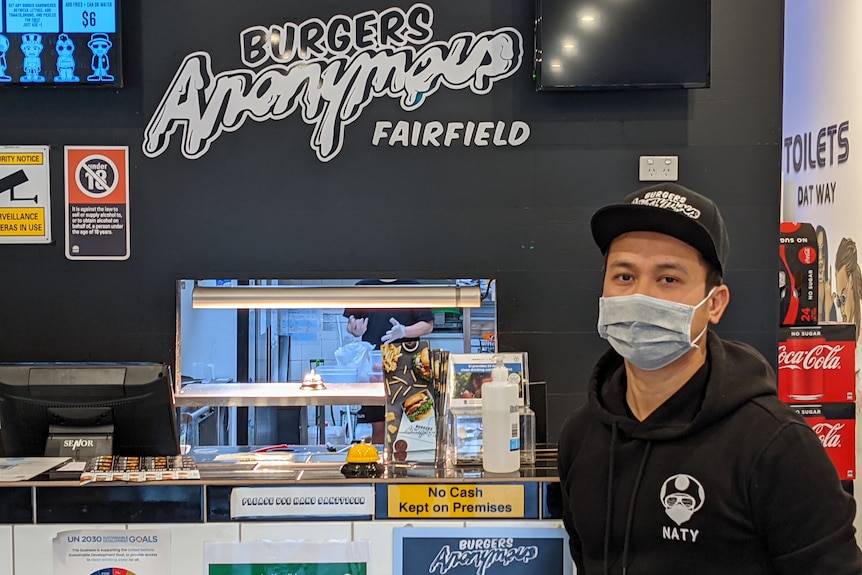 Naty heng wears a mask while standing in his empty burger shop in Fairfield.