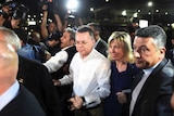 Pastor Andrew Brunson grasps the hand of his wife as they arrive at an airport surrounded by media.