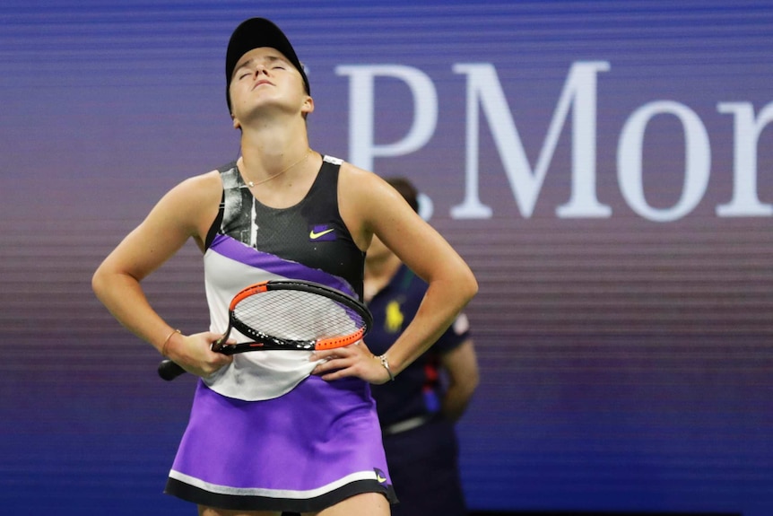 Elina Svitolina holds both her hands on her hips and looks up at the sky