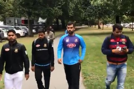 Several men in training gear walk quickly through a park in Christchurch.