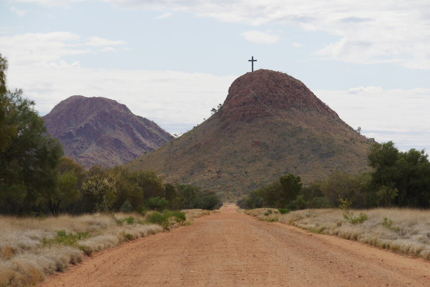 Una cruz se sienta encima de una montaña en Australia Central