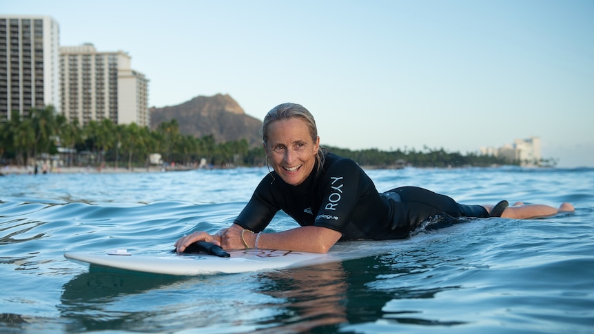 woman in surf with buildings in the background