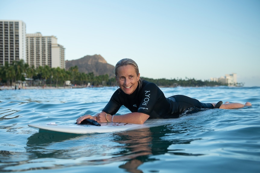 woman in surf with buildings in the background