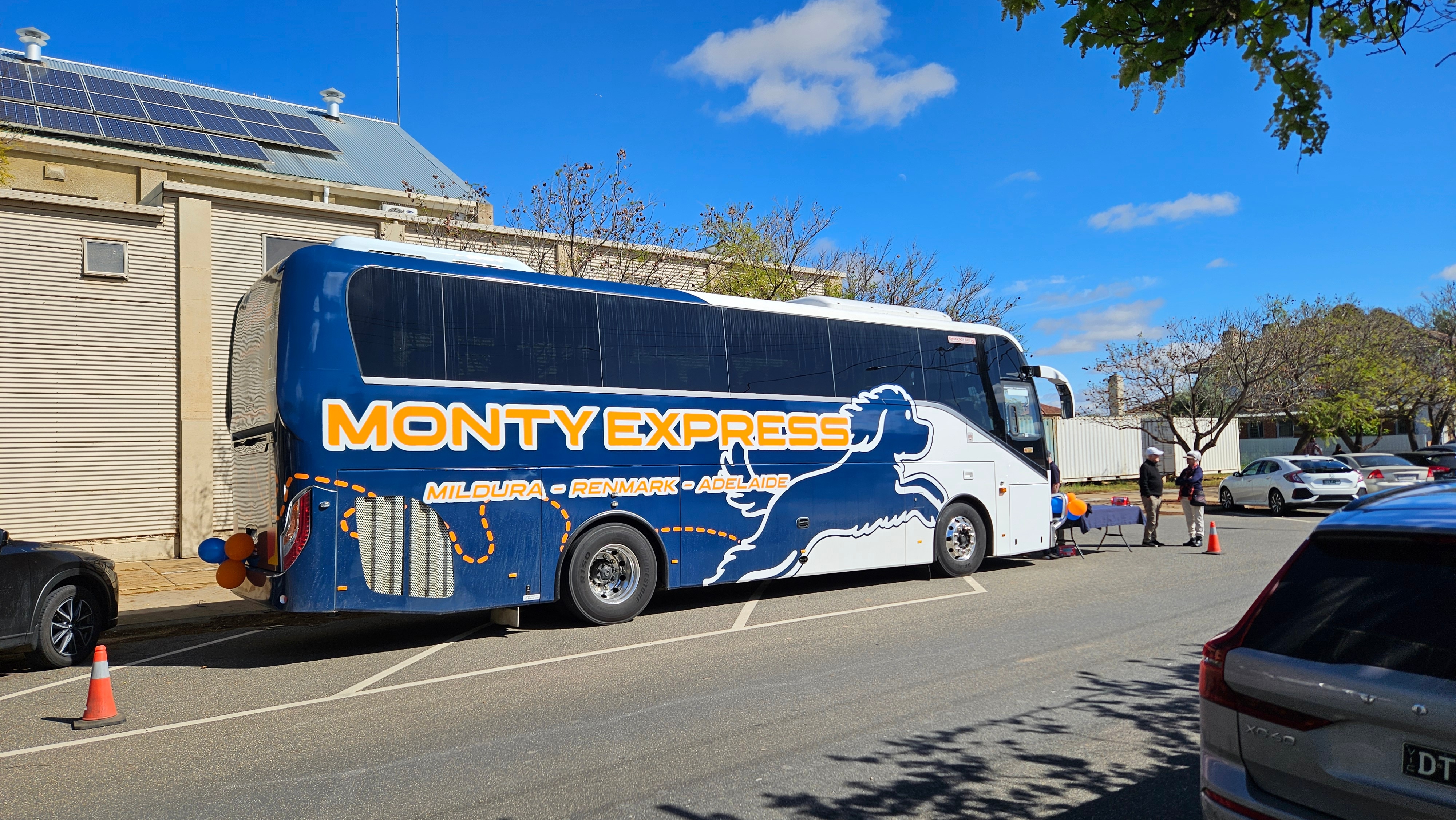 A bus with blue, white and orange livery, which says The Monty Express
