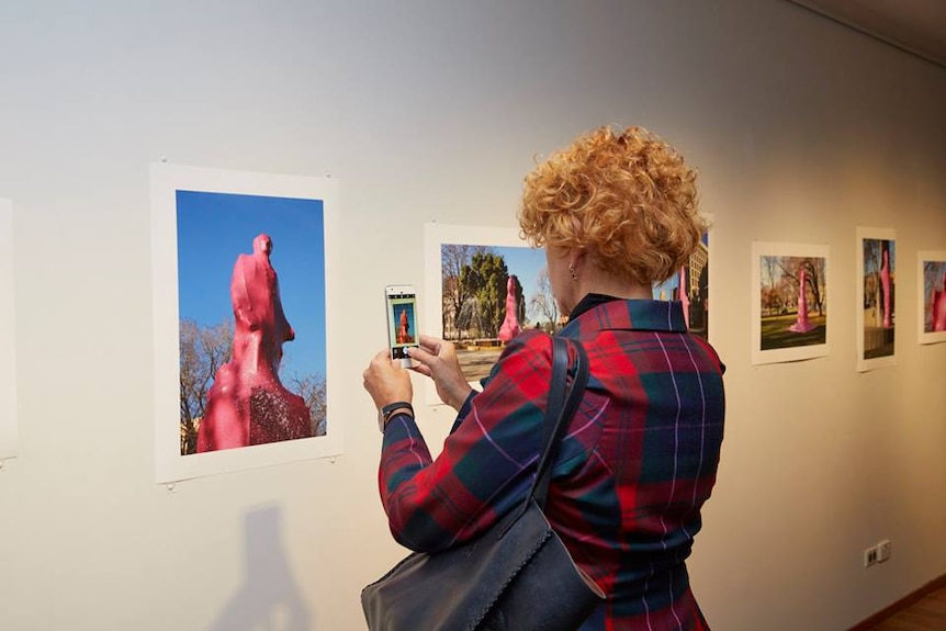 Woman taking in the artworks at the New Sacred exhibition