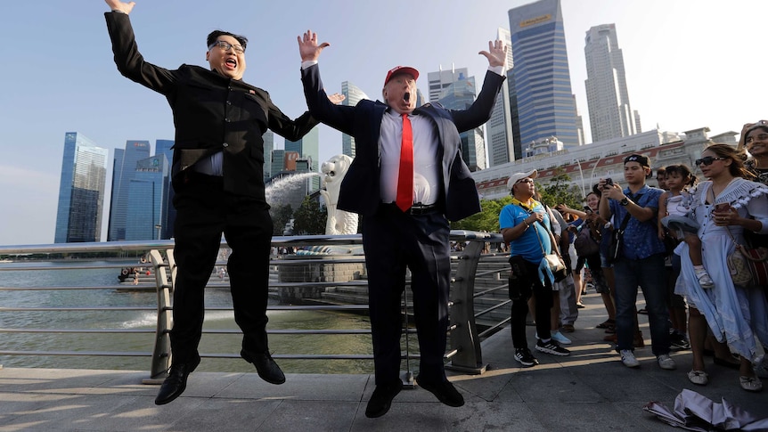 Kim Jong Un and Donald Trump impersonators leap in the air in front of a crowd