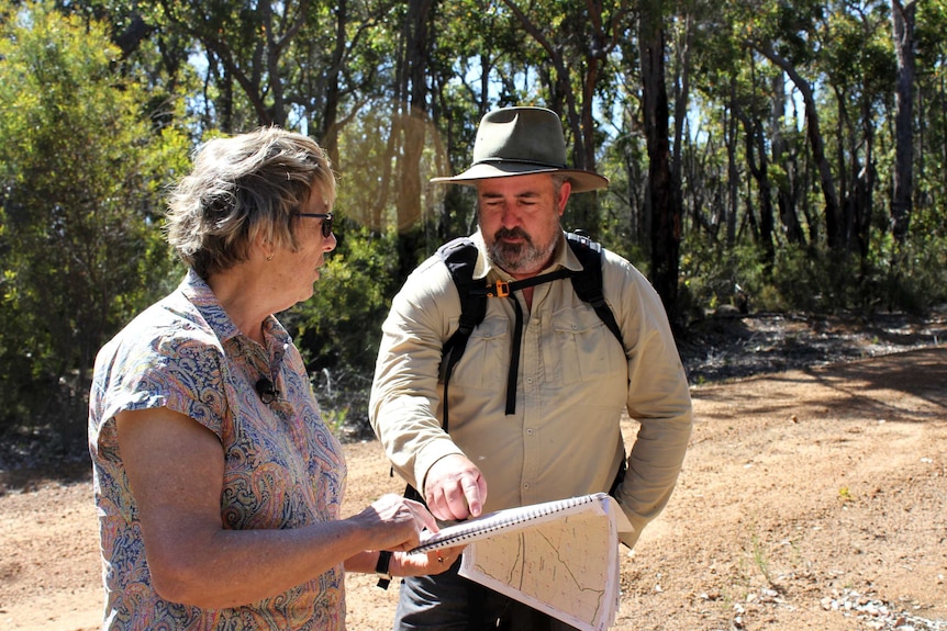 A man and woman examine a map standing on a roadside