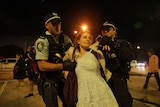 Two police officers hold a woman by the arms at a pro-Palestinian rally 
