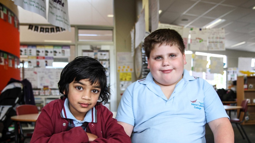 Year Two students, Hasaru and Aiden sit at a classroom desk wearing school uniforms.